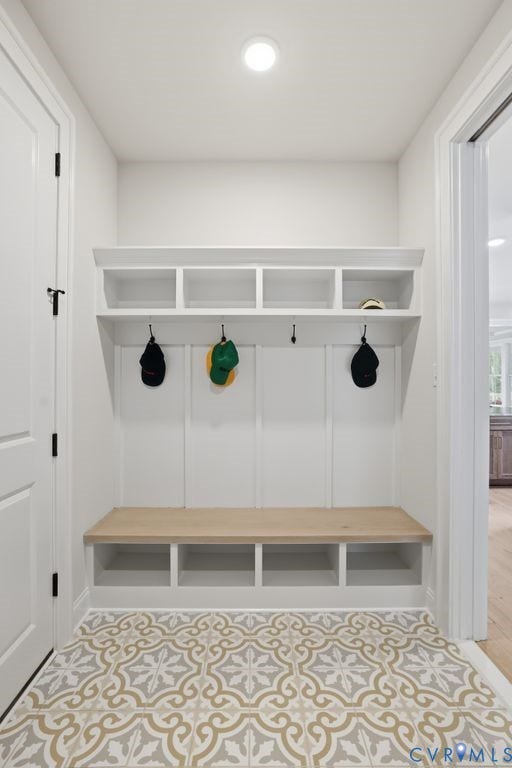 Built-in storage bench with wood-finish seating and overhead cubbies, complemented by decorative floor tiling