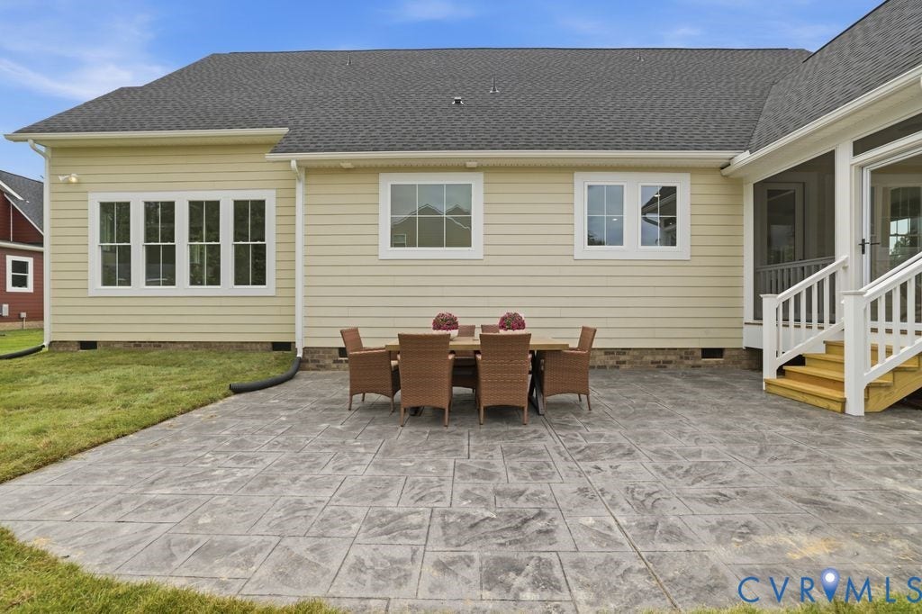 Expansive stamped concrete patio with direct access to a screened porch via wooden stairs
