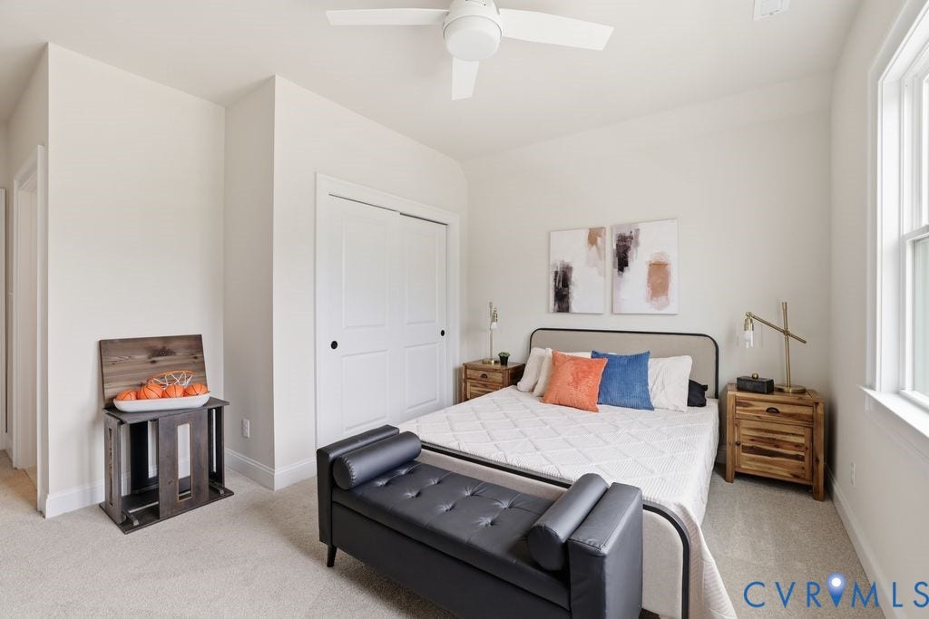 Carpeted bedroom featuring a ceiling fan, a window with white trim, and a built-in closet with bi-fold doors