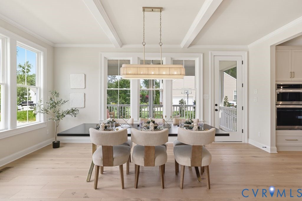 Dining area featuring coffered ceilings, light wood-finish flooring, and multiple windows