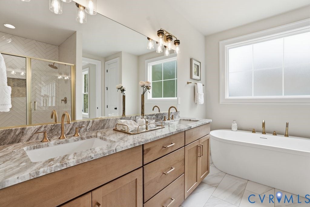 Bathroom featuring a double vanity with stone countertops, undermount sinks, and gold-finish fixtures