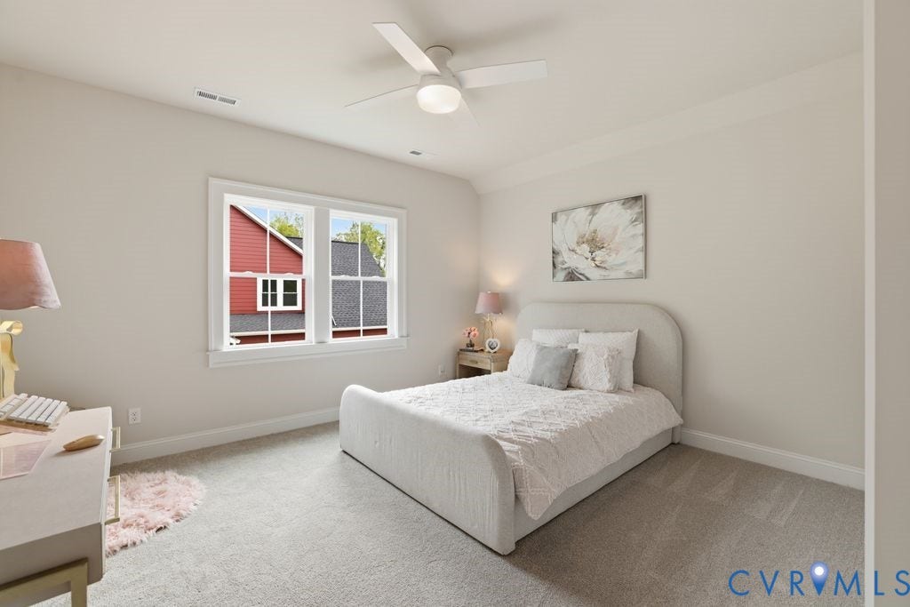 Light-filled room featuring neutral wall tones, plush carpet flooring, a white ceiling fan with integrated lighting, and a double window with white trim