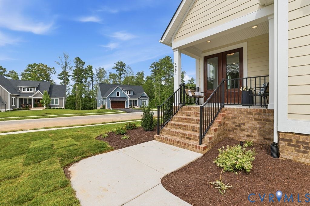 Inviting front porch featuring a brick foundation, dark wood entry doors, and contrasting light-colored siding