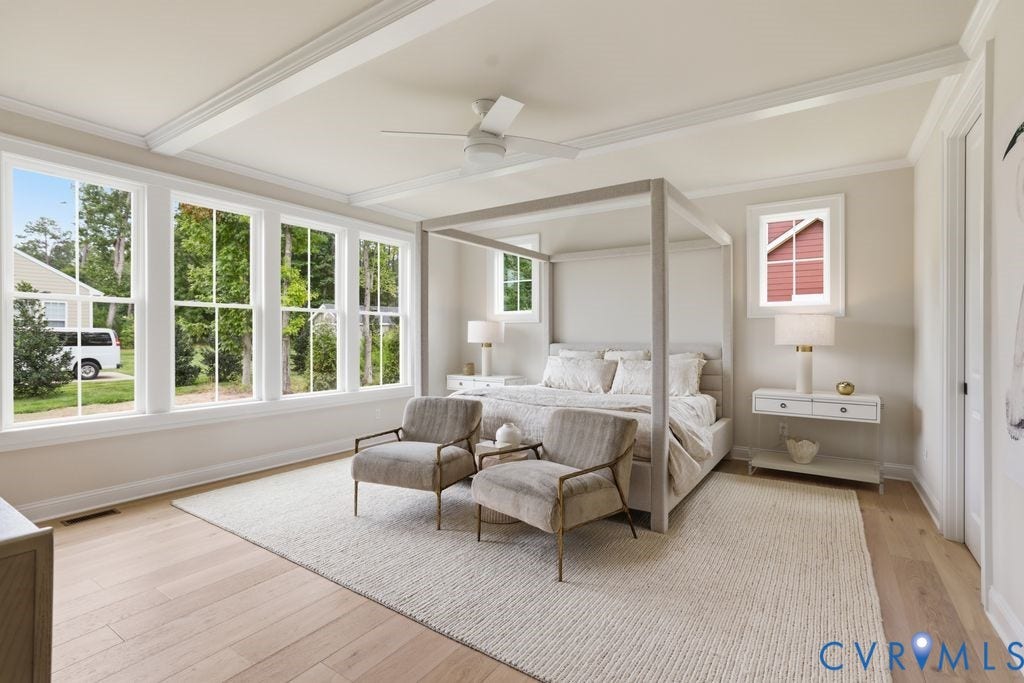 Spacious room featuring light wood-finish flooring, a tray ceiling with crown molding, and multiple large windows with white trim