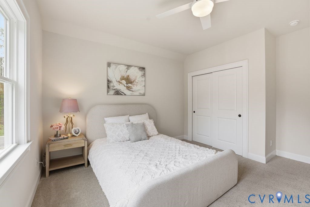Carpeted room featuring a white ceiling fan with integrated lighting, a double window with white trim, and a bi-fold closet with black hardware