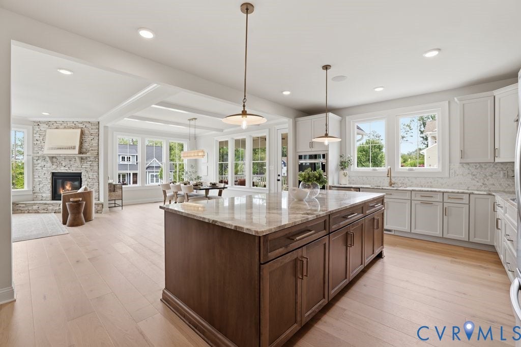 Gourmet kitchen featuring a large wood-finish island with stone countertop, white perimeter cabinetry, and light wood-finish flooring