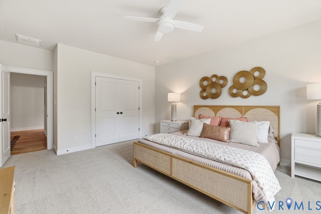 Carpeted bedroom with a white ceiling fan and light-toned walls