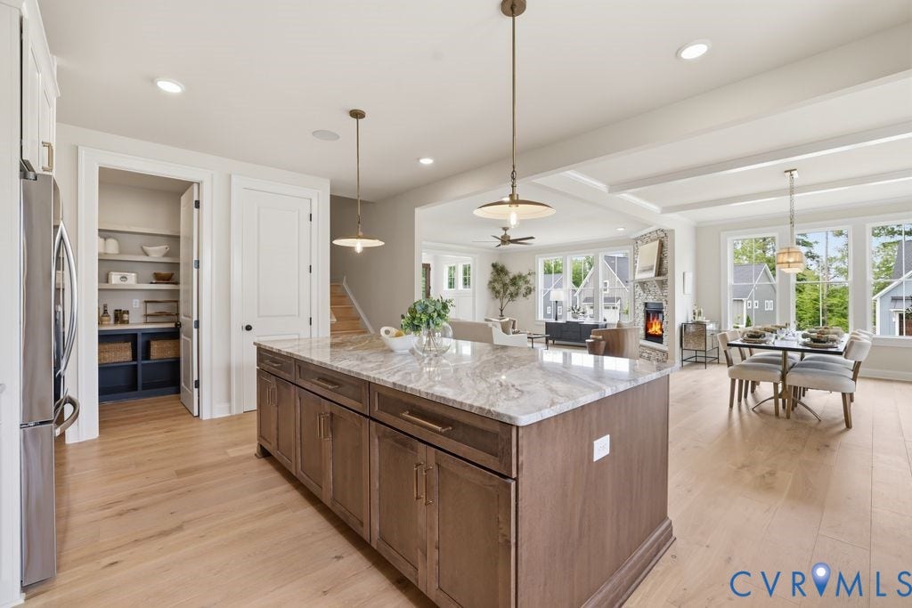 Kitchen island featuring extensive cabinet storage, a light-toned countertop, and two pendant light fixtures