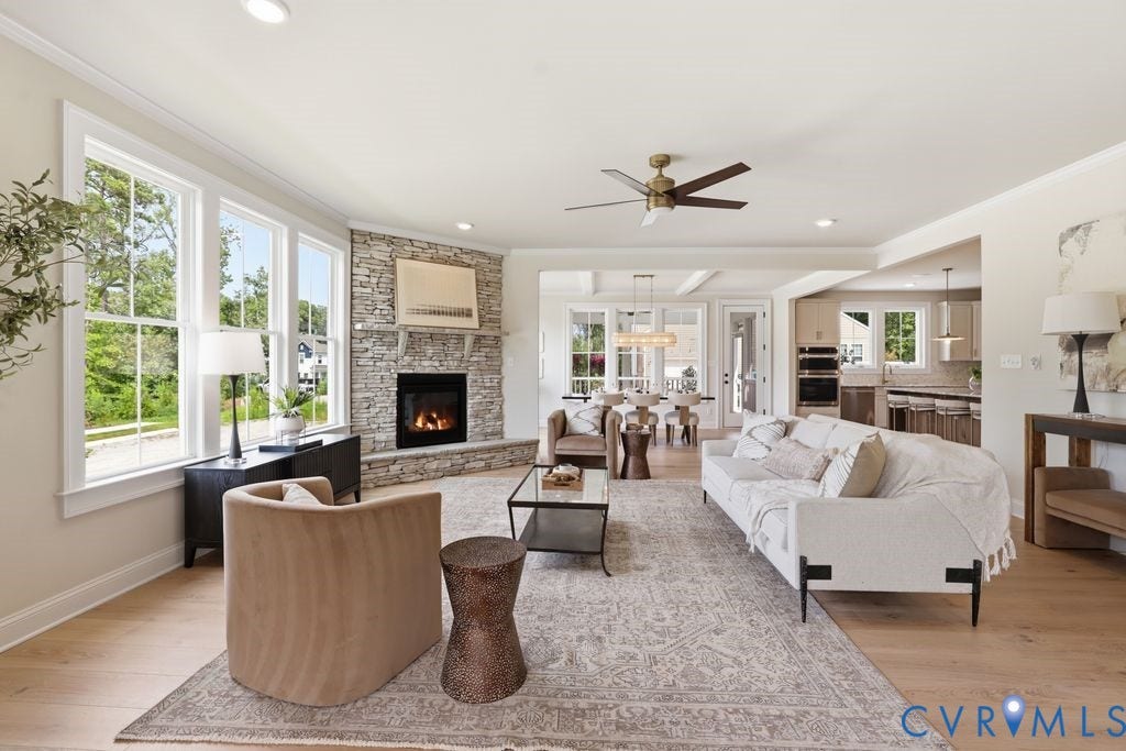 Open-concept living space featuring wood-finish flooring, recessed lighting, and a stacked stone fireplace
