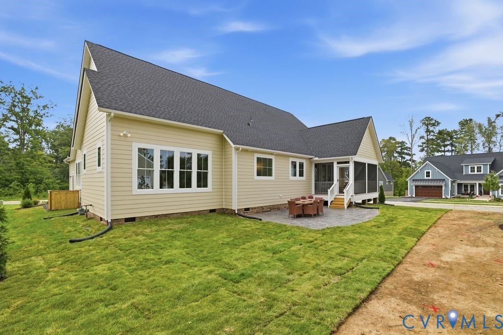 Rear exterior featuring light-toned siding, a dark shingle roof, and multiple white-framed windows