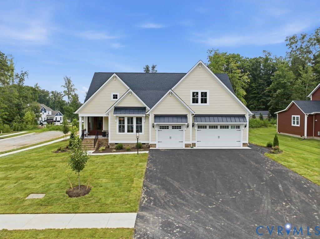 Traditional-style home featuring light-toned siding, a dark shingle roof, and a two-car garage