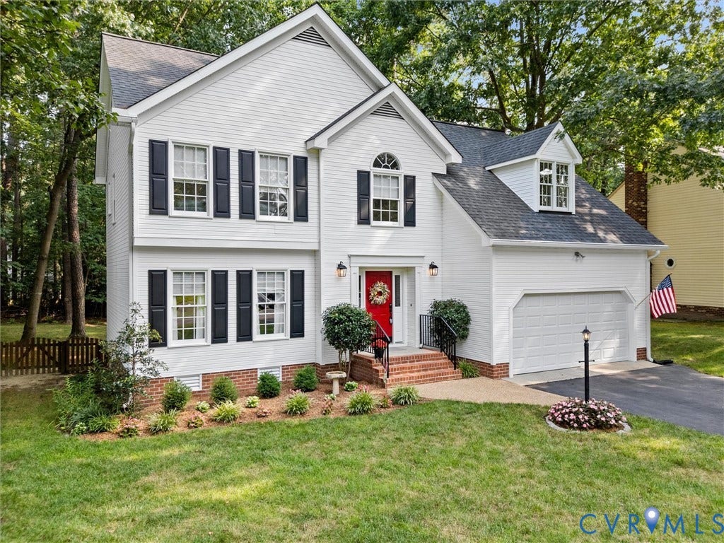13915 Highpaige Way, Stoney Glen West, Chester, VA 23831 Two-story white residence with black shutters, a red front door, an attached garage, a dormer window, and mature surrounding trees