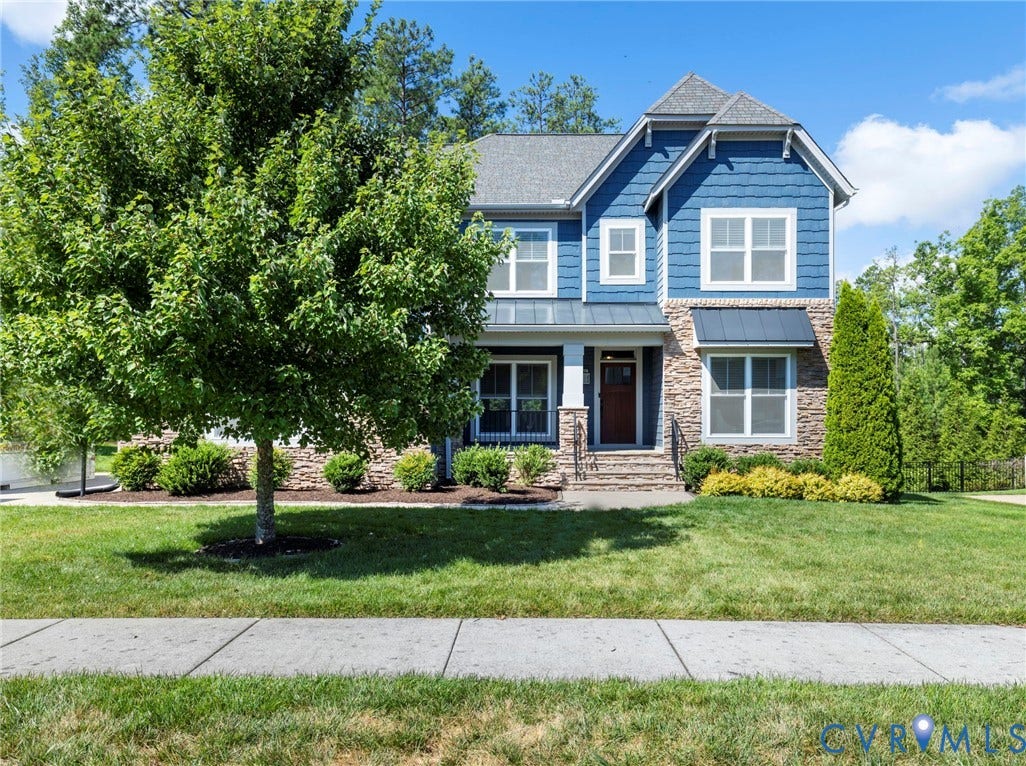 6984 Carden Park Drive, Moseley, VA 23120 Two-story residence featuring blue Hardie-plank siding and stone facade with standing seam awnings, sidewalk, mature landscaping, broom swept concrete porch, 2 car side load garage.