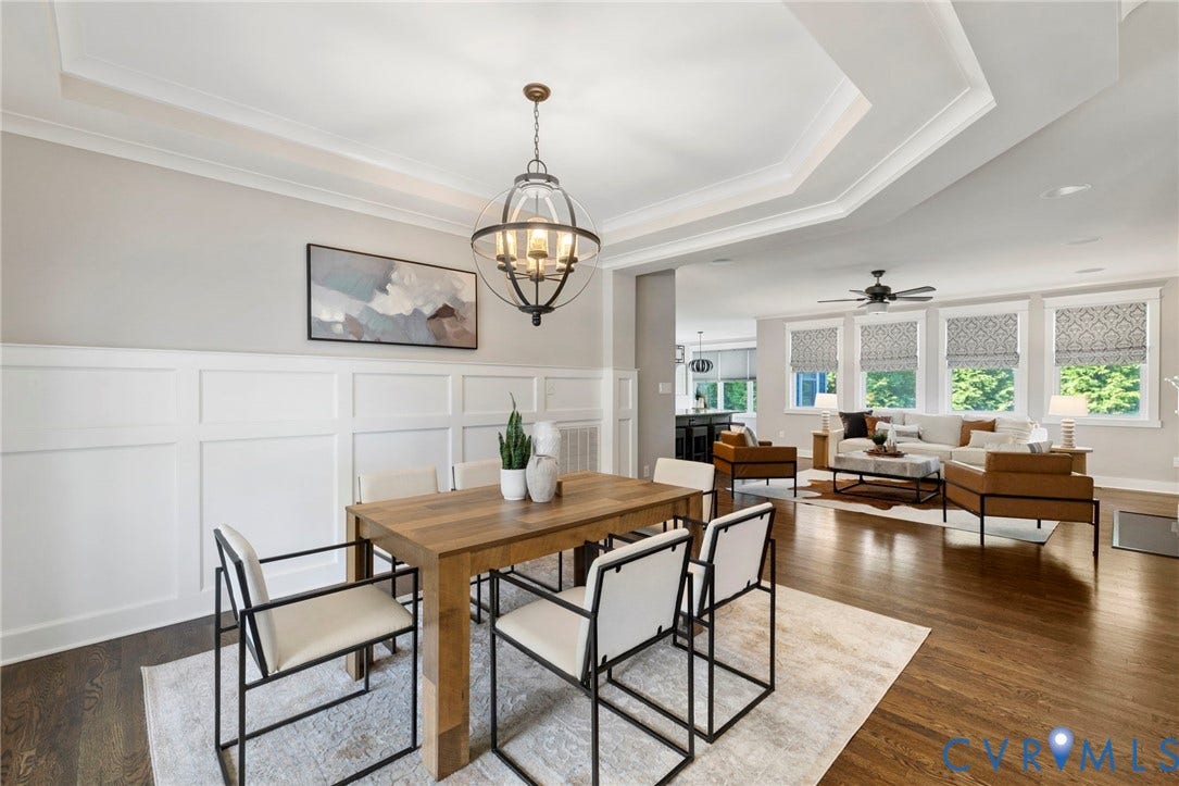 6984 Carden Park Drive, Moseley, VA 23120 Open-concept living and dining areas featuring site finished hard wood-flooring, white wainscoting, and tray ceilings