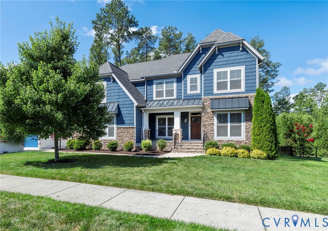 6984 Carden Park Drive, Moseley, VA 23120 Two-story residence featuring blue Hardie-plank siding and stone facade with standing seam awnings, sidewalk, mature landscaping, broom swept concrete porch, 2 car side load garage.