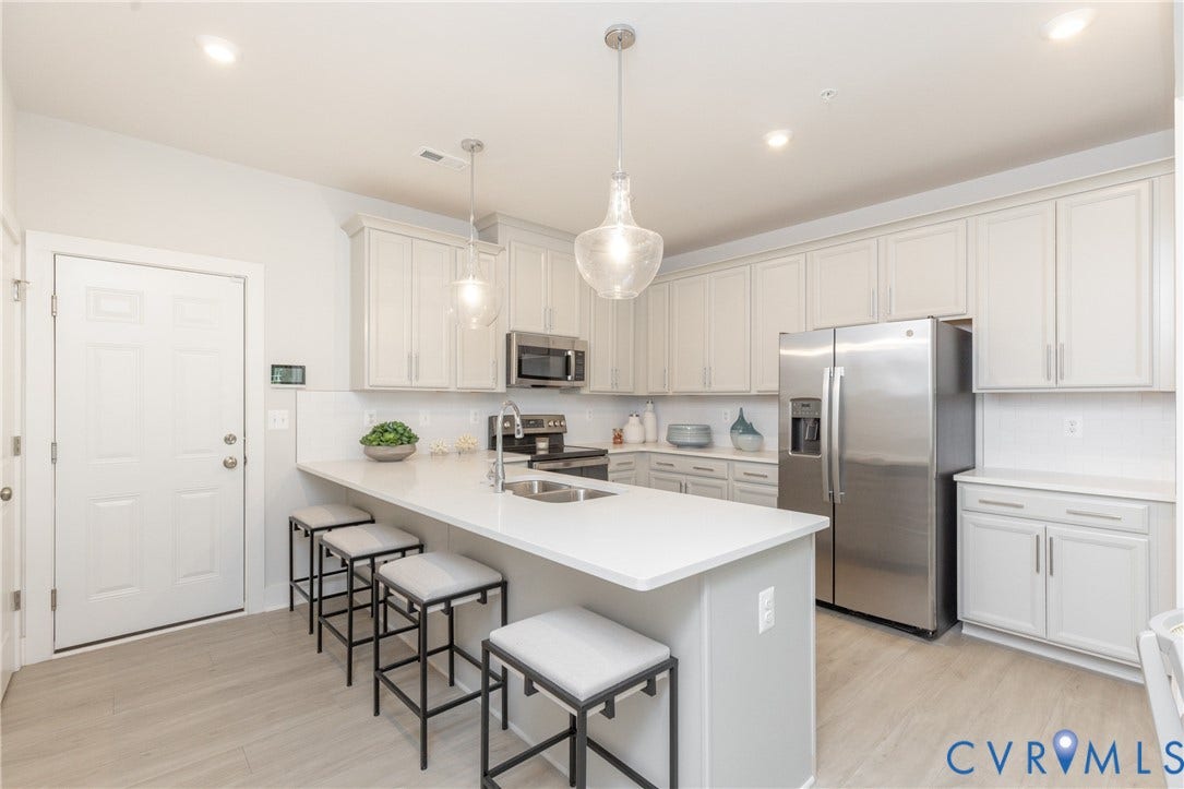 1041 N Lombardy Street, #A, Carver Square, Richmond, VA 23220 Modern kitchen featuring light cabinetry, stainless steel appliances, a white subway tile backsplash, & a large island with seating