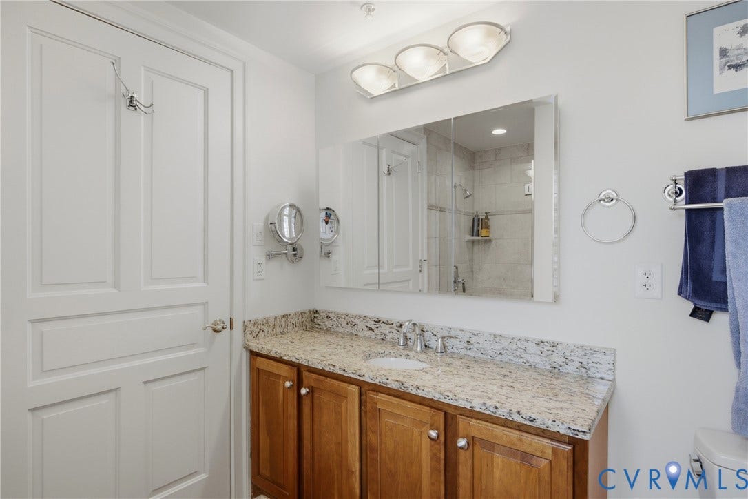 Bathroom vanity featuring a light-toned countertop, wood-finish cabinetry, and a mirrored medicine cabinet