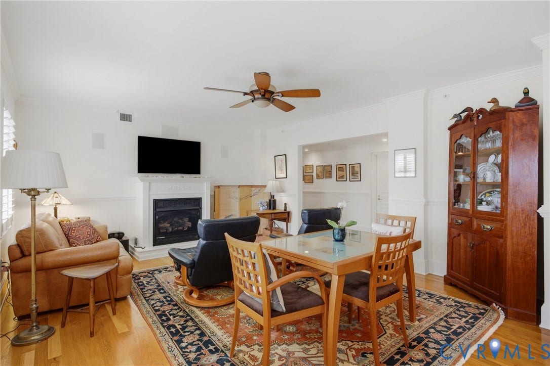 Living area with wood-finish flooring, white walls, and a ceiling fan