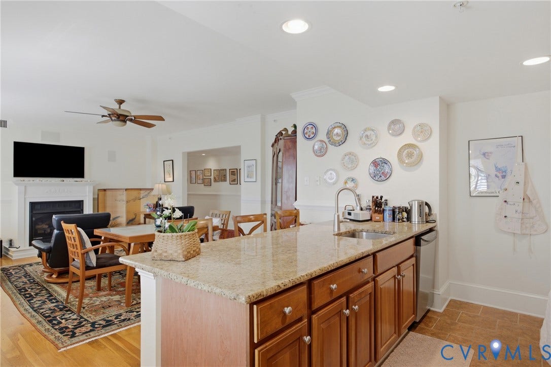 Kitchen island with a light granite countertop, undermount sink, and wood cabinetry