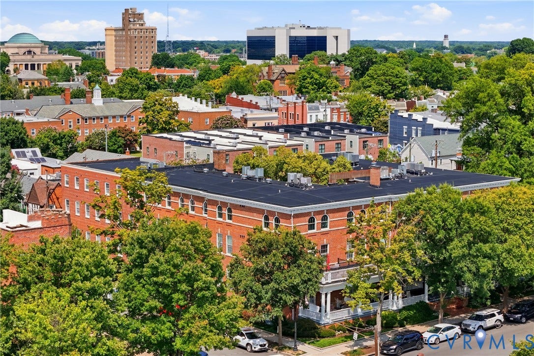 Historic brick architecture featuring multiple arched windows, a flat roof, and a covered porch with white columns