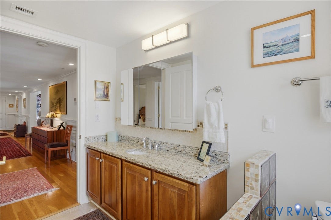 Bathroom vanity with a light-toned stone countertop, integrated sink, and wood cabinetry