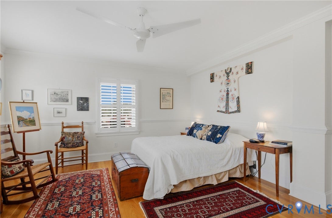 Bright bedroom featuring a ceiling fan, crown molding, white plantation shutters, chair rail molding, and wood-finish flooring