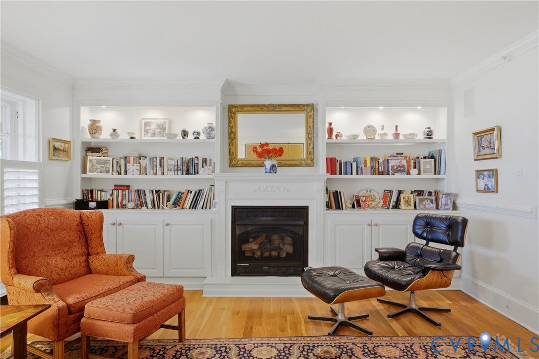 Hardwood flooring accents a living space featuring a built-in fireplace with an ornate mantel and integrated shelving with accent lighting