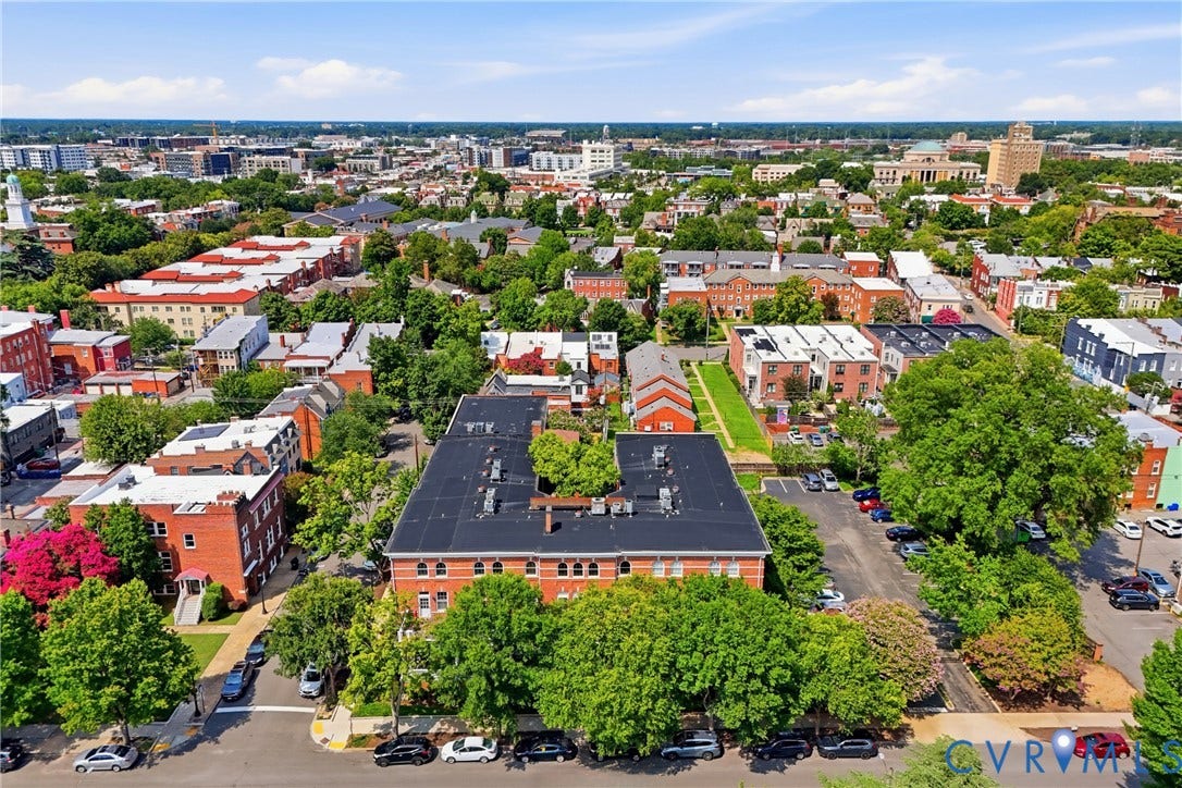 Expansive aerial view showcasing a multi-story brick building with a dark roof