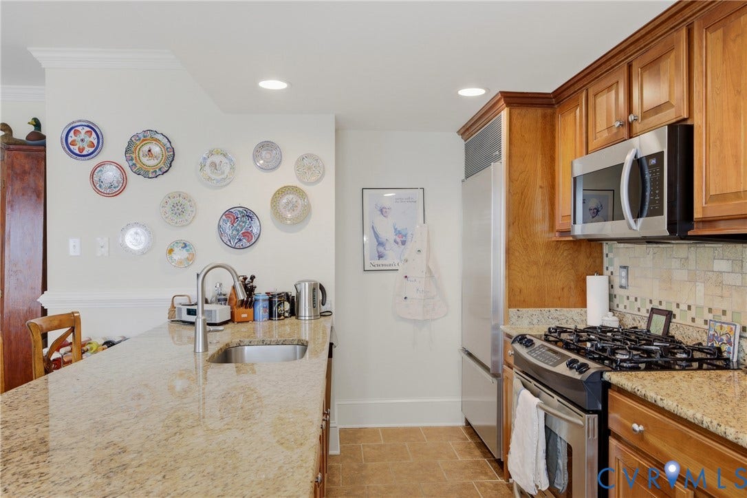 Kitchen featuring an expansive island with an undermount sink, granite countertops, and light wood cabinetry