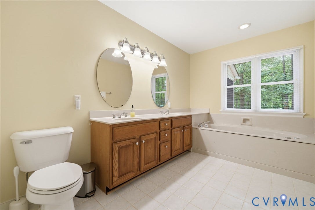 1902 Soldiers Lane, Crozier, VA 23039 Spacious bathroom featuring a double vanity with wood-finish cabinetry, dual oval mirrors, and a six-light vanity fixture