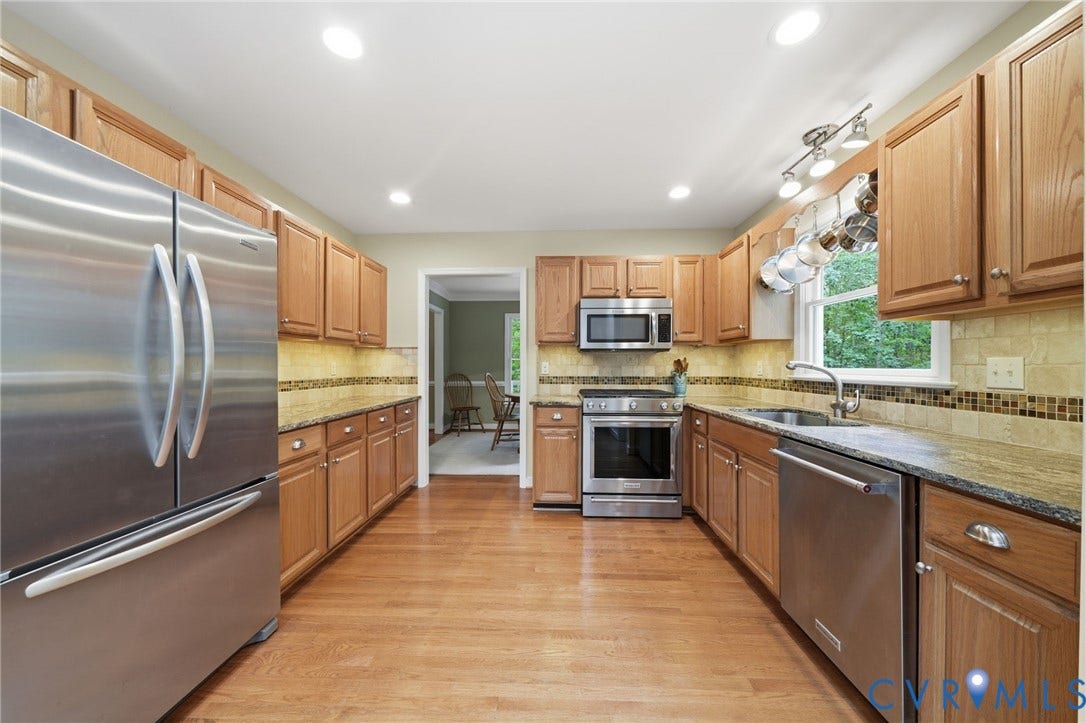 1902 Soldiers Lane, Crozier, VA 23039 Kitchen featuring wood-finish flooring, stainless steel appliances, upper and lower wood cabinetry, stone countertops, and a tiled backsplash