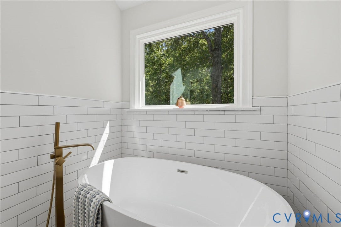 3457 Richards Run, Very Desirable!, Powhatan, VA 23139 Freestanding soaking tub with a floor-mounted bronze-finish faucet, subway tile wainscoting, and a white framed window