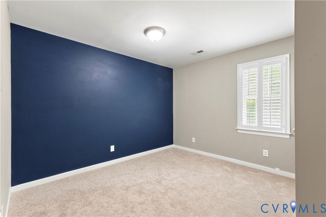5117 Hart Mill Drive, Glen Allen, VA 23060 Room featuring an accent wall, neutral wall colors, textured carpet, white baseboards, and a window with white plantation shutters