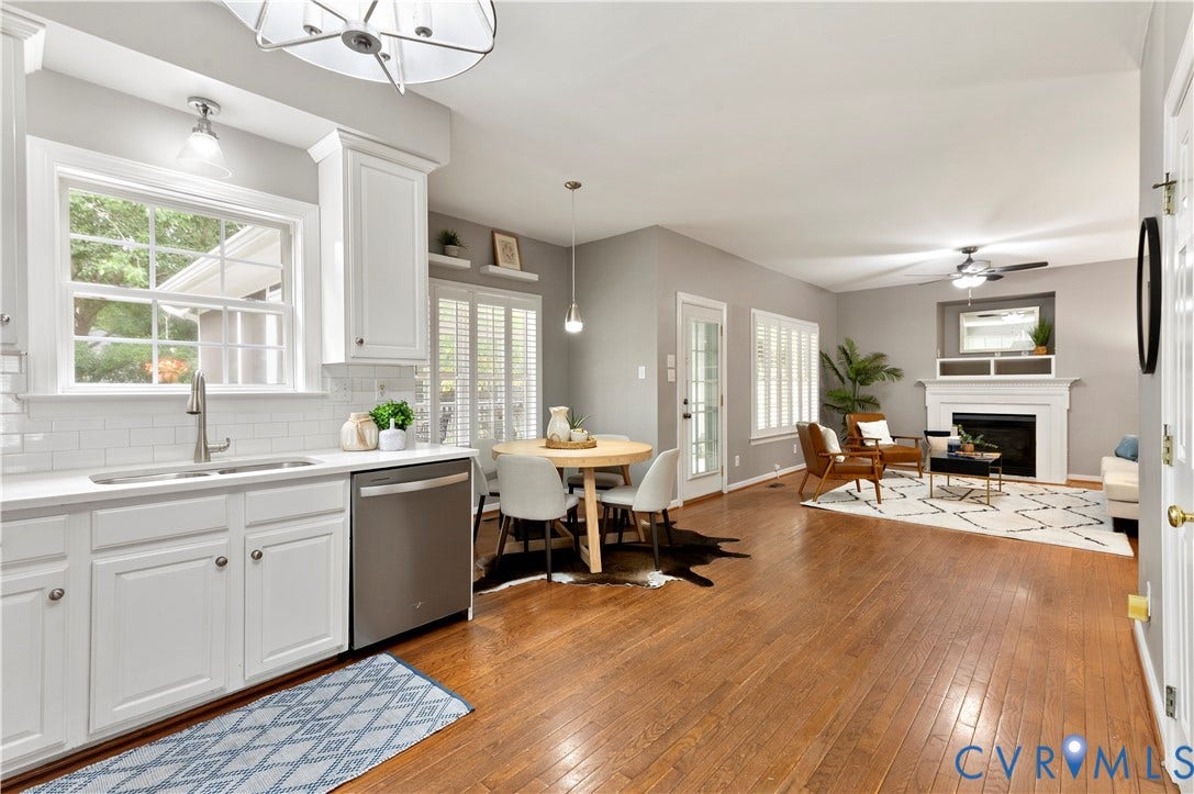 5117 Hart Mill Drive, Glen Allen, VA 23060 Open-concept living area with wood-finish flooring, a kitchen featuring white cabinetry and subway tile backsplash, and a dining area with plantation shutters