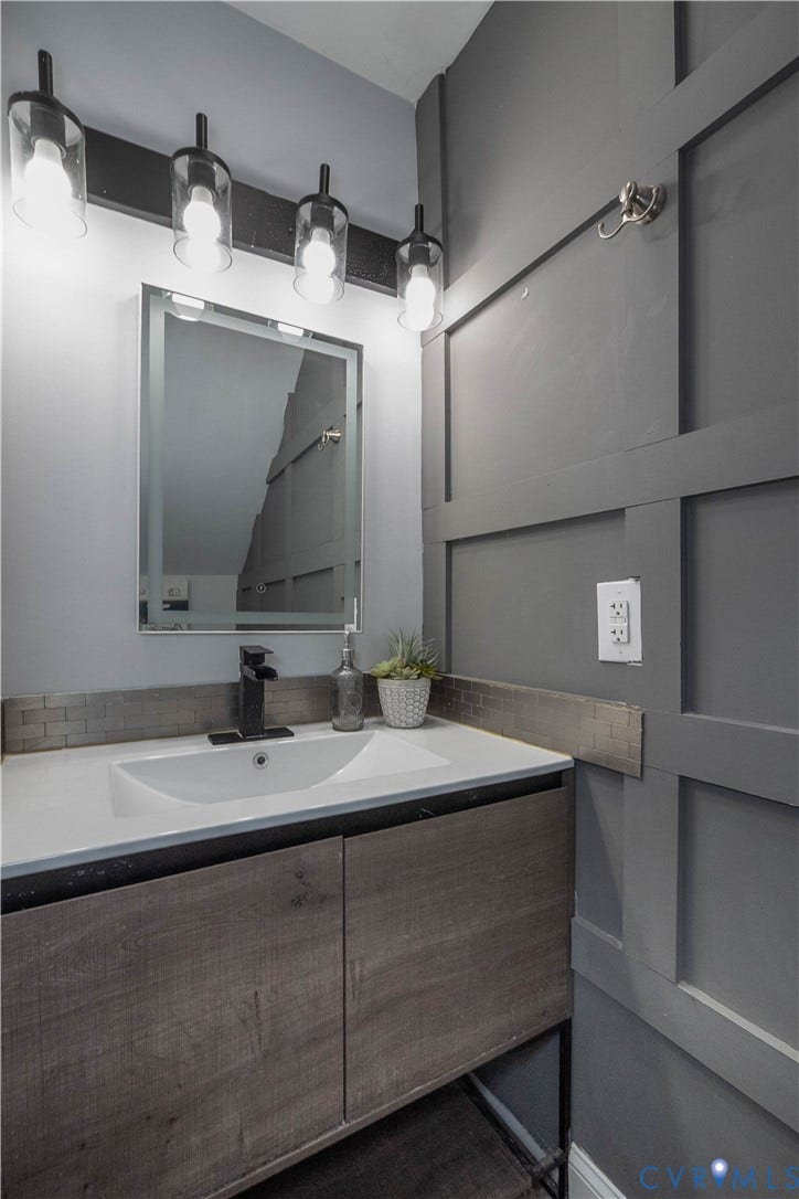 1209 N 22nd Street, Church Hill, Richmond, VA 23223 Bathroom vanity featuring a white rectangular sink, a matte black faucet, and a wood-finish cabinet with two doors