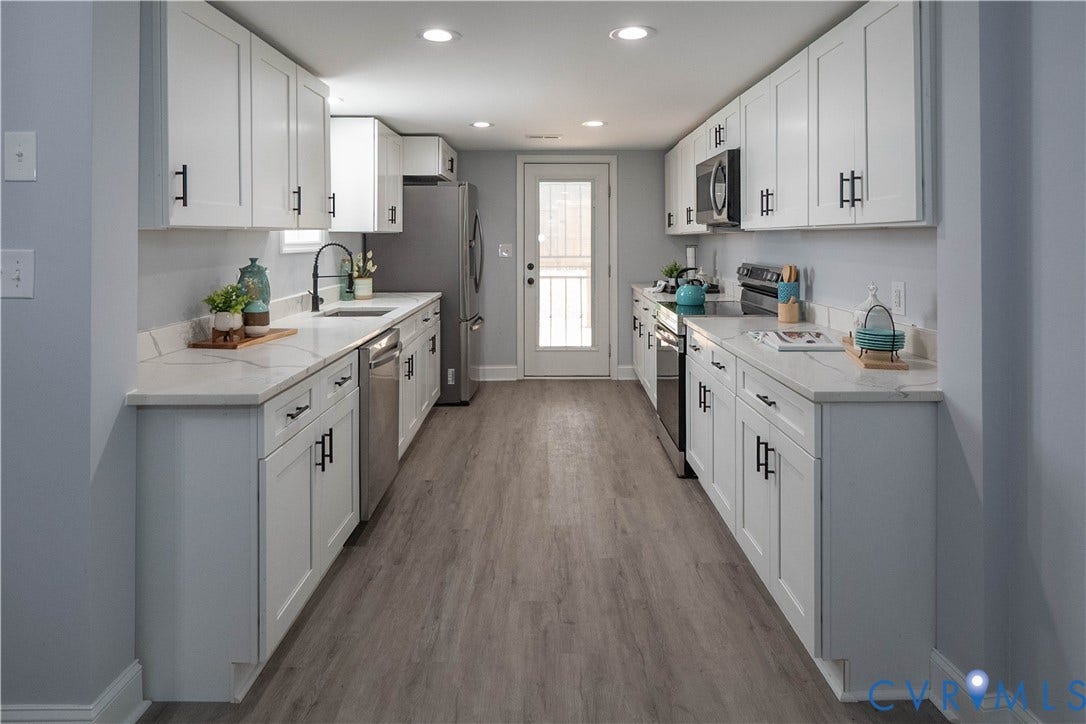 1209 N 22nd Street, Church Hill, Richmond, VA 23223 Galley kitchen featuring white shaker cabinetry with black hardware, light-toned countertops, wood-finish flooring, and stainless steel appliances