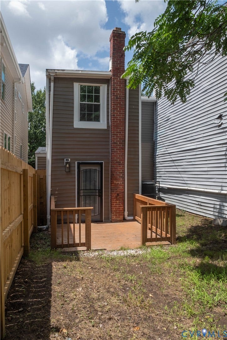 1209 N 22nd Street, Church Hill, Richmond, VA 23223 Private rear yard with a wood fence, featuring a ground-level wood deck with railings and a brick chimney