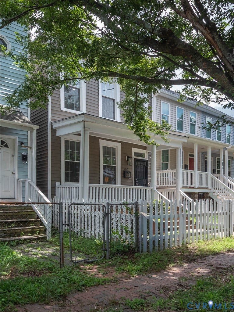 1209 N 22nd Street, Church Hill, Richmond, VA 23223 Two-story residence featuring a covered front porch with white railing, a white picket fence, and a brick pathway