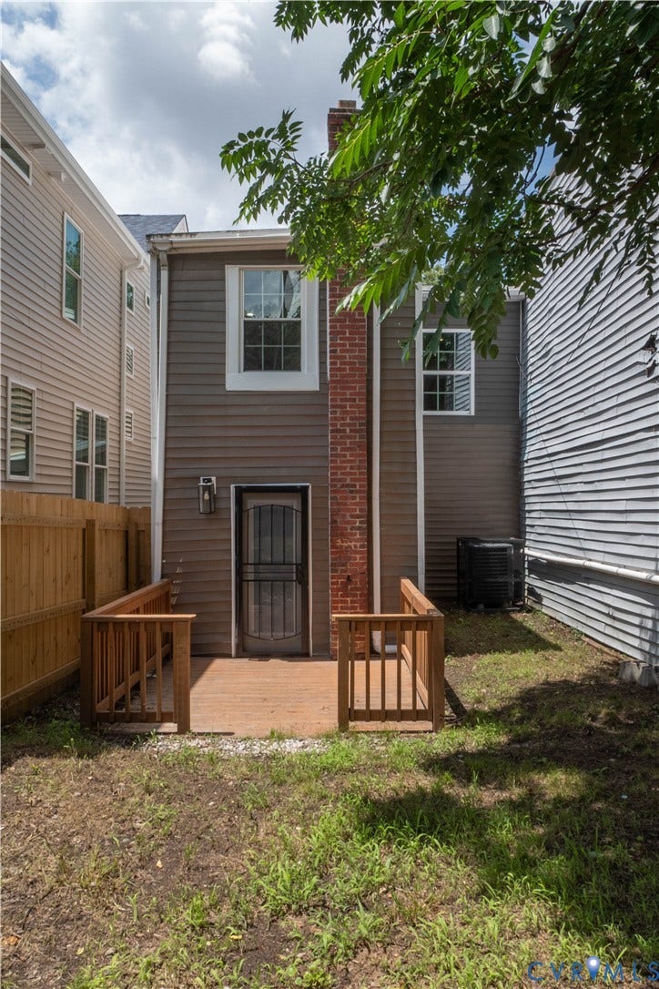 1209 N 22nd Street, Church Hill, Richmond, VA 23223 Rear exterior featuring a wood deck with railings, a brick chimney, and two upper-story windows