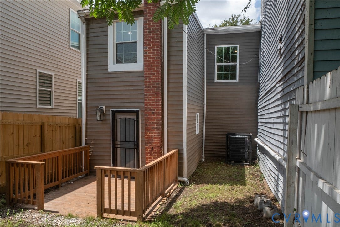 1209 N 22nd Street, Church Hill, Richmond, VA 23223 Rear exterior featuring a wood-plank ramp leading to a metal-grate door, a brick chimney, and horizontal siding