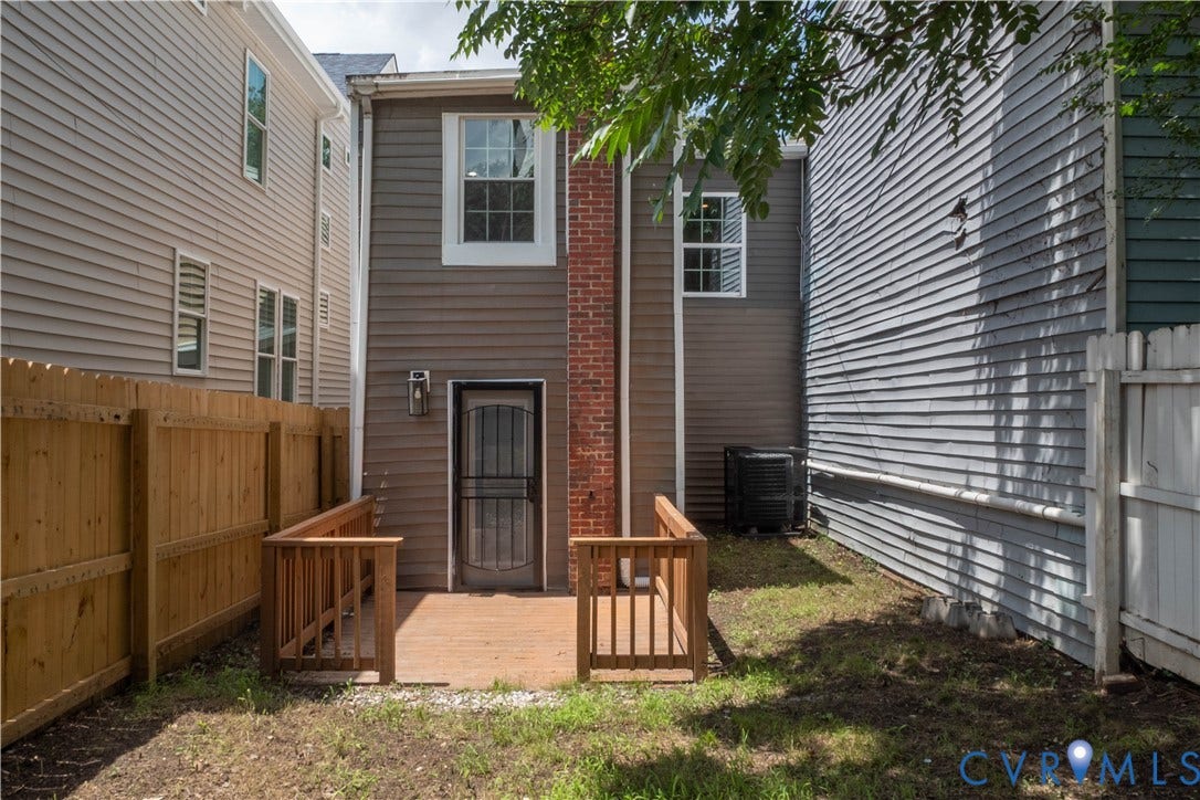 1209 N 22nd Street, Church Hill, Richmond, VA 23223 Rear exterior featuring a wooden deck with railing, a security door, and a brick chimney accent