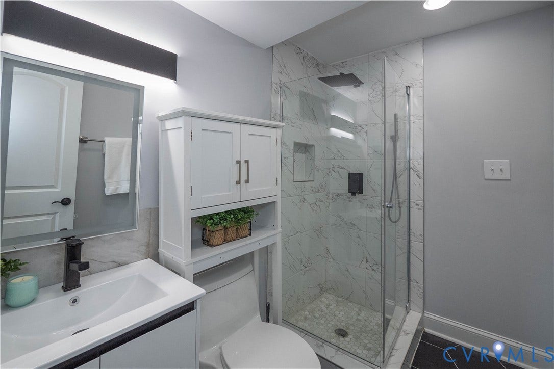 1209 N 22nd Street, Church Hill, Richmond, VA 23223 Contemporary bathroom featuring a glass-enclosed shower with marble-look tile, a rain showerhead, and a built-in niche