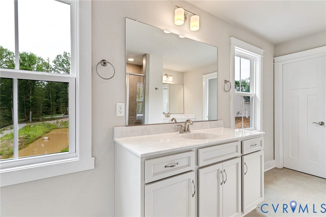 11101 Somerset Hill Drive, Somerset Hills, Glen Allen, VA 23059 White vanity with an integrated sink, dual windows, large frameless mirror, and overhead vanity lighting