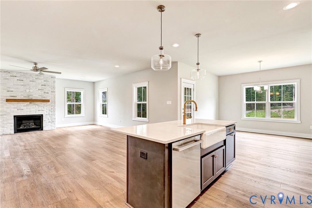 11101 Somerset Hill Drive, Somerset Hills, Glen Allen, VA 23059 Open-concept living space featuring wood-finish flooring, a white brick fireplace with a wood mantle, an island with a farm sink, and pendant lighting