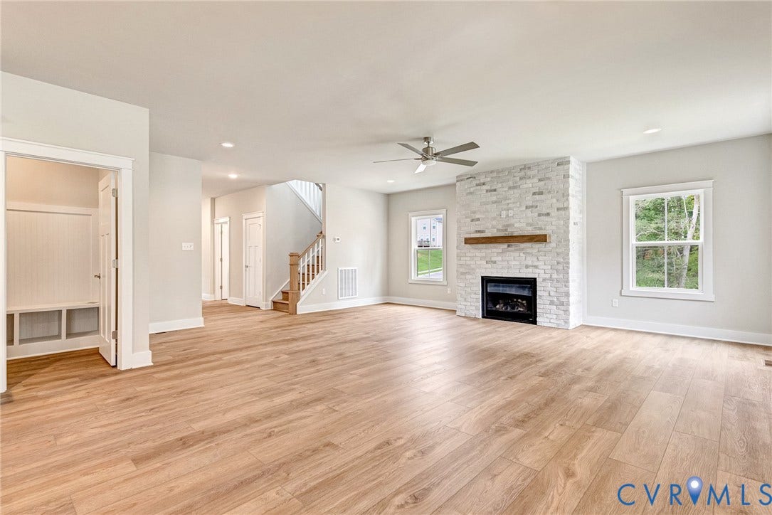 11101 Somerset Hill Drive, Somerset Hills, Glen Allen, VA 23059 Wide-plank wood-finish flooring, white brick fireplace with dark hearth, built-in mudroom bench with beadboard paneling, and a contemporary ceiling fan