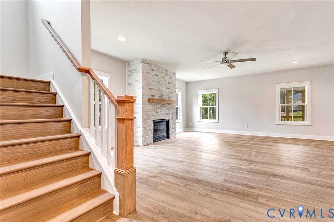 11101 Somerset Hill Drive, Somerset Hills, Glen Allen, VA 23059 Wood-finish flooring, staircase with wood newel post and handrail, ceiling fan, and a stone-clad fireplace with a wood mantel