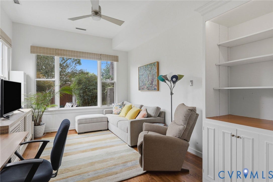 404 N Shields Avenue, Richmond, VA 23220 Bright living area featuring significant natural light, high ceilings, wood-finish flooring, a contemporary ceiling fan, and built-in shelving with lower cabinetry