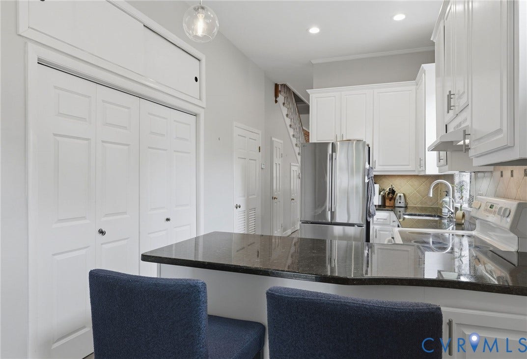 404 N Shields Avenue, Richmond, VA 23220 Modern kitchen featuring white cabinetry, stainless steel appliances, dark stone countertops, a breakfast bar, and a tile backsplash