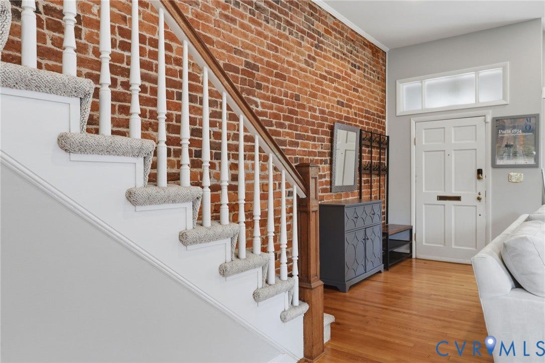 404 N Shields Avenue, Richmond, VA 23220 Entryway featuring a prominent exposed brick wall, hardwood flooring, and a paneled front door with a transom window