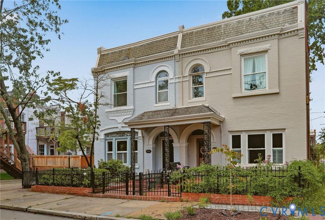 404 N Shields Avenue, Richmond, VA 23220 Historic townhome facade featuring a mansard roof, arched windows, covered porch with decorative columns, and a wrought iron fence